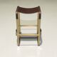 Bar stool in aged brass and brown leather.