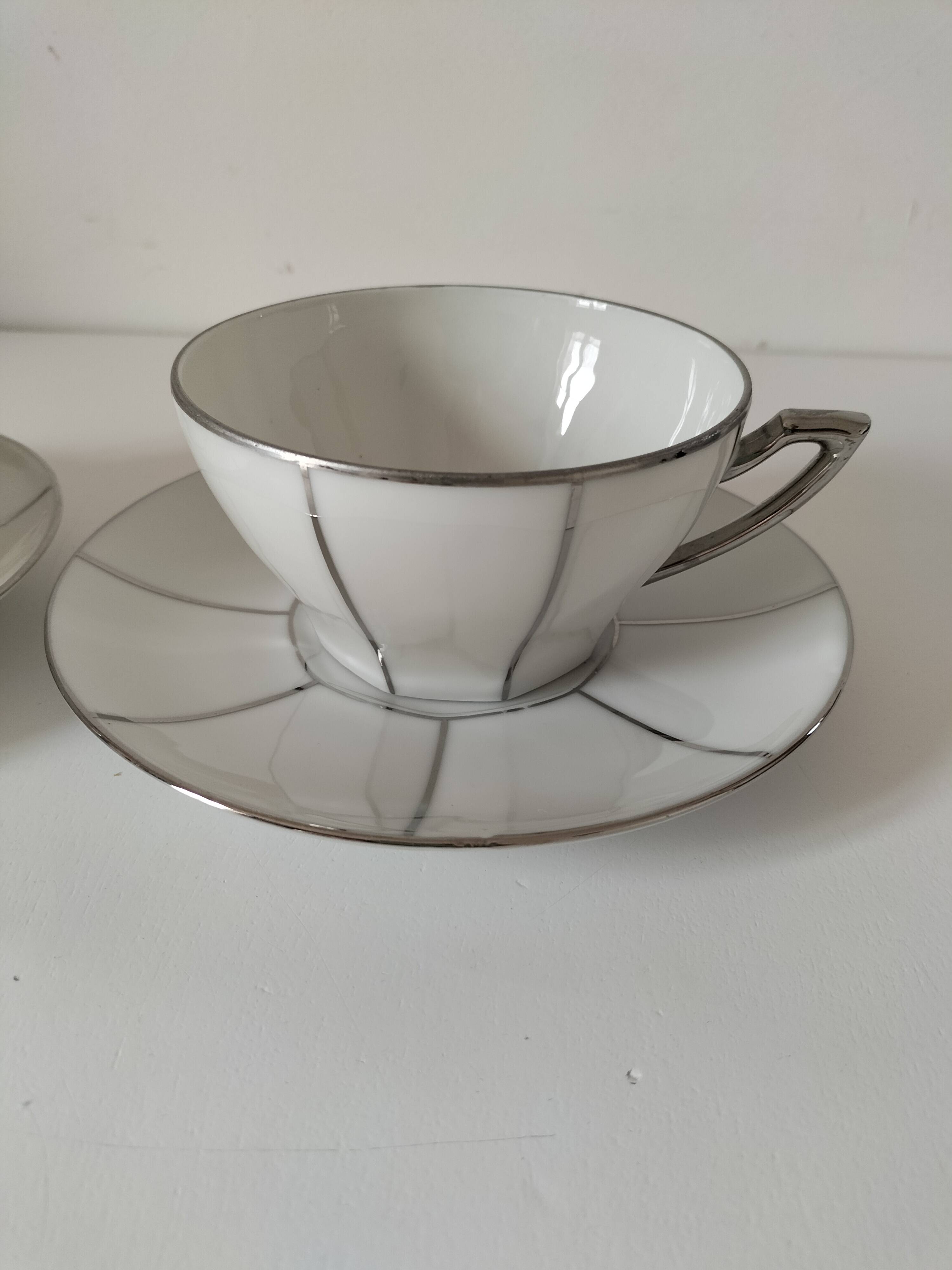 Two Art Deco porcelain cups and saucers with silver trim.