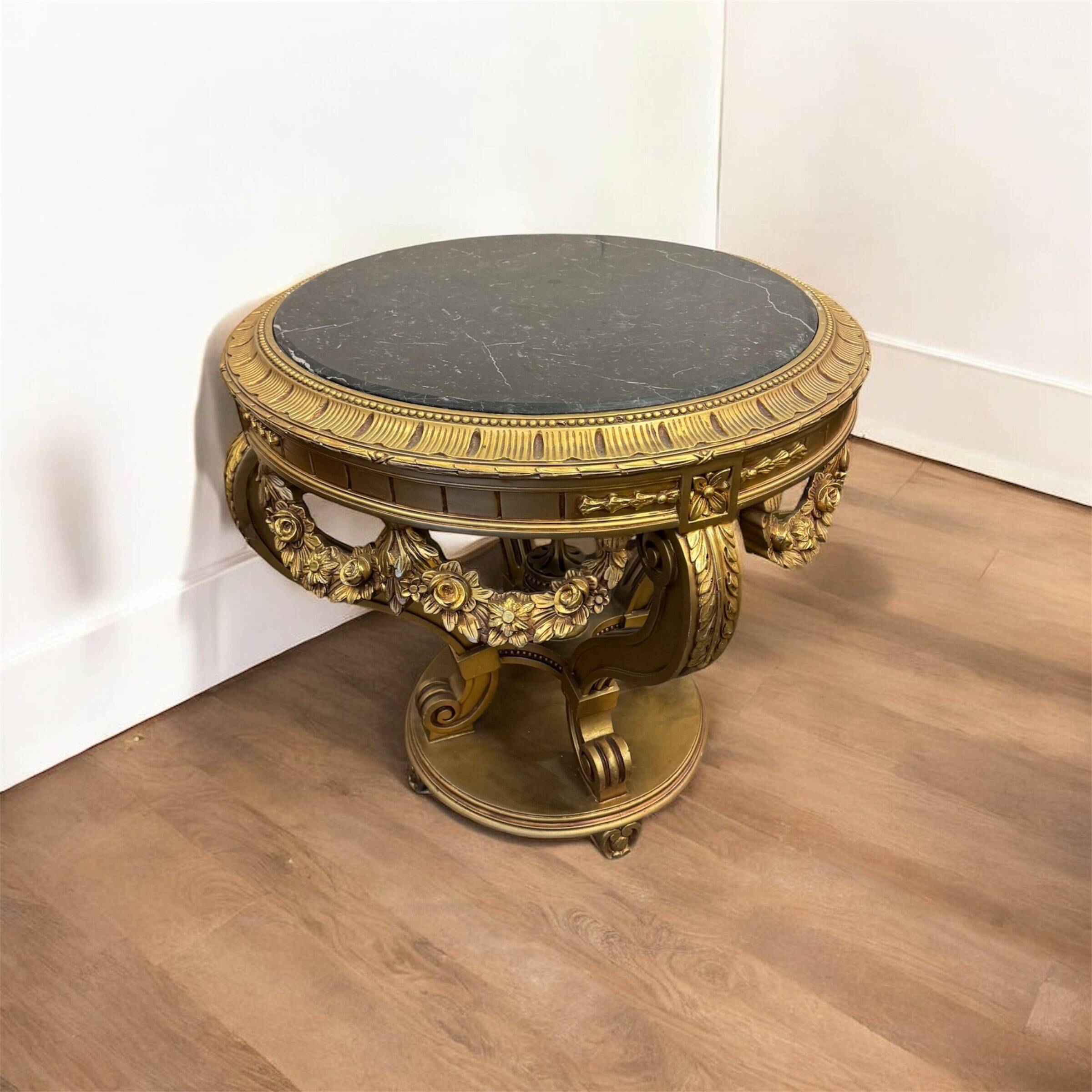 A round Louis XV style table in carved gilt beechwood with a black marble top
