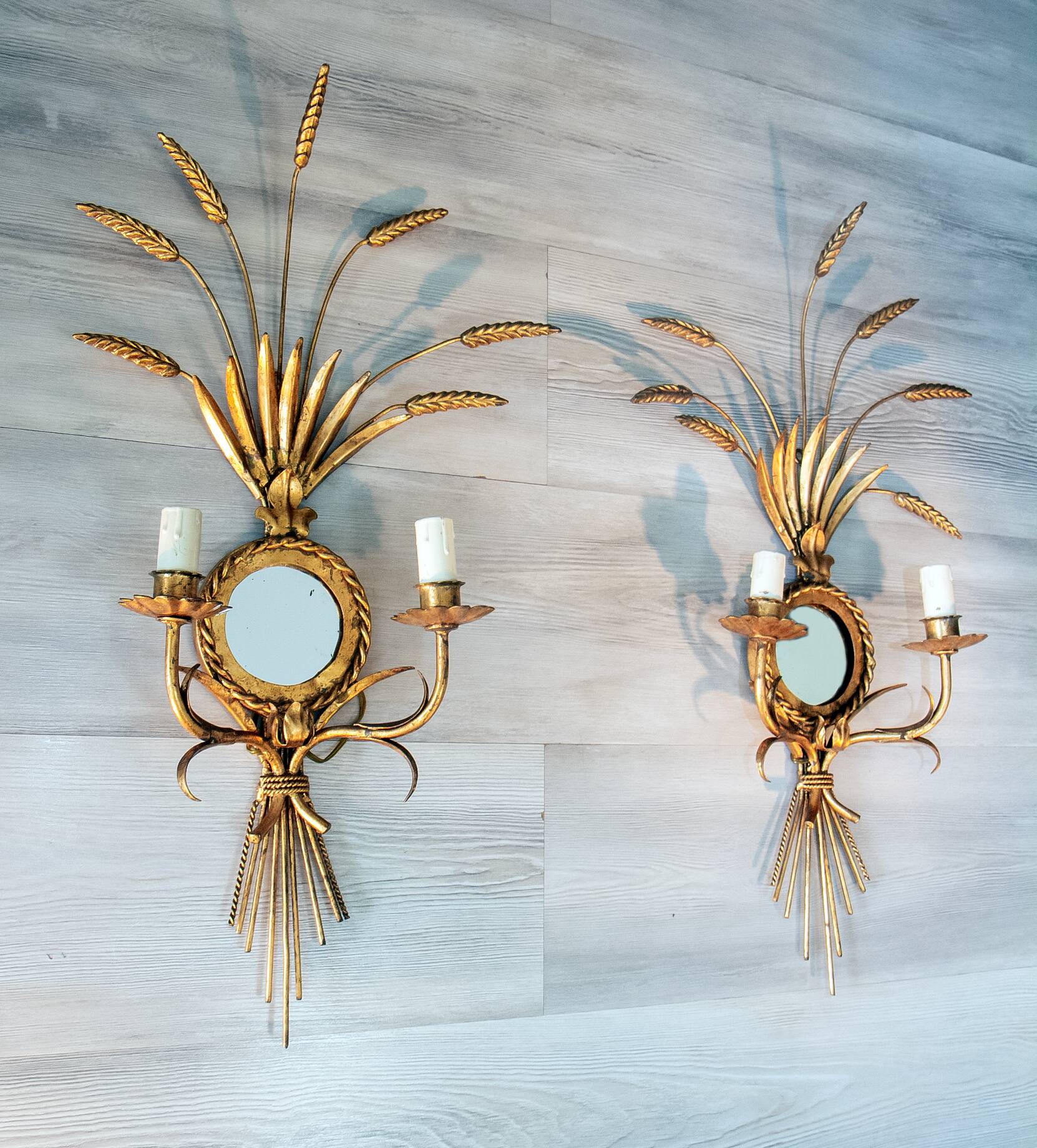 A pair of 1950s wall sconces in gold leaf metal.