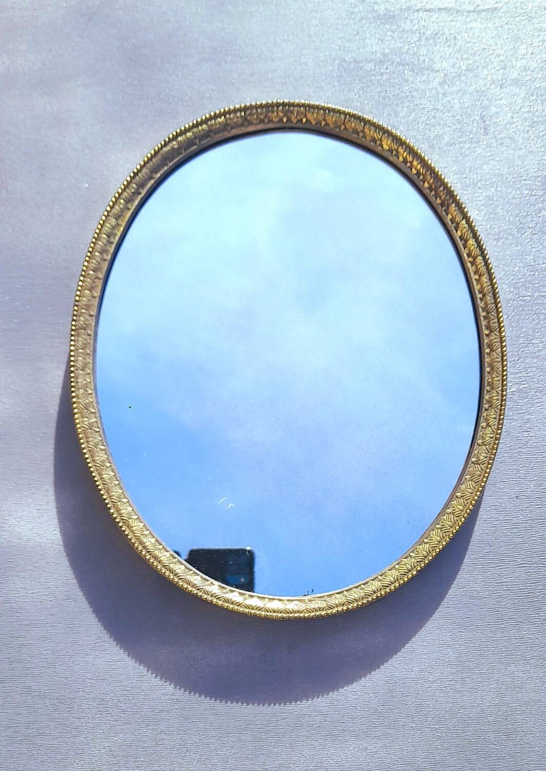 Oval mirror in gold metal