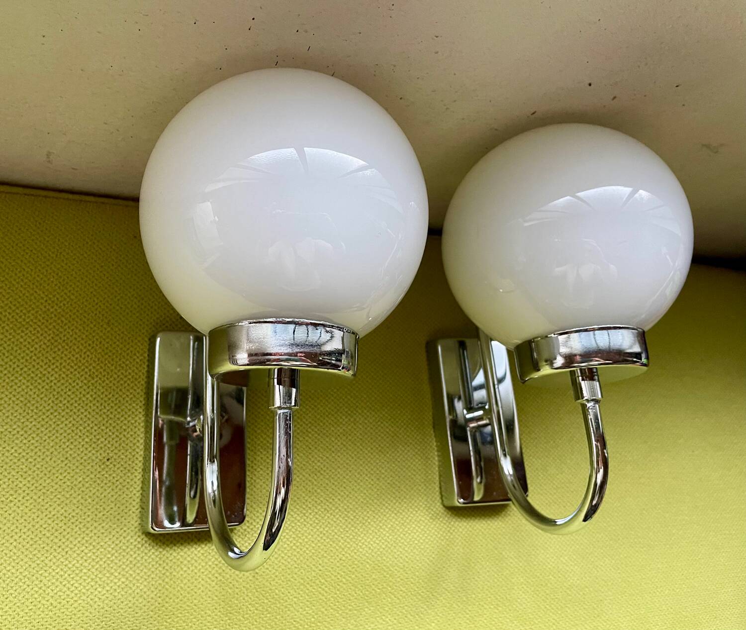 Pair of chrome metal wall lights with white glass globe.
