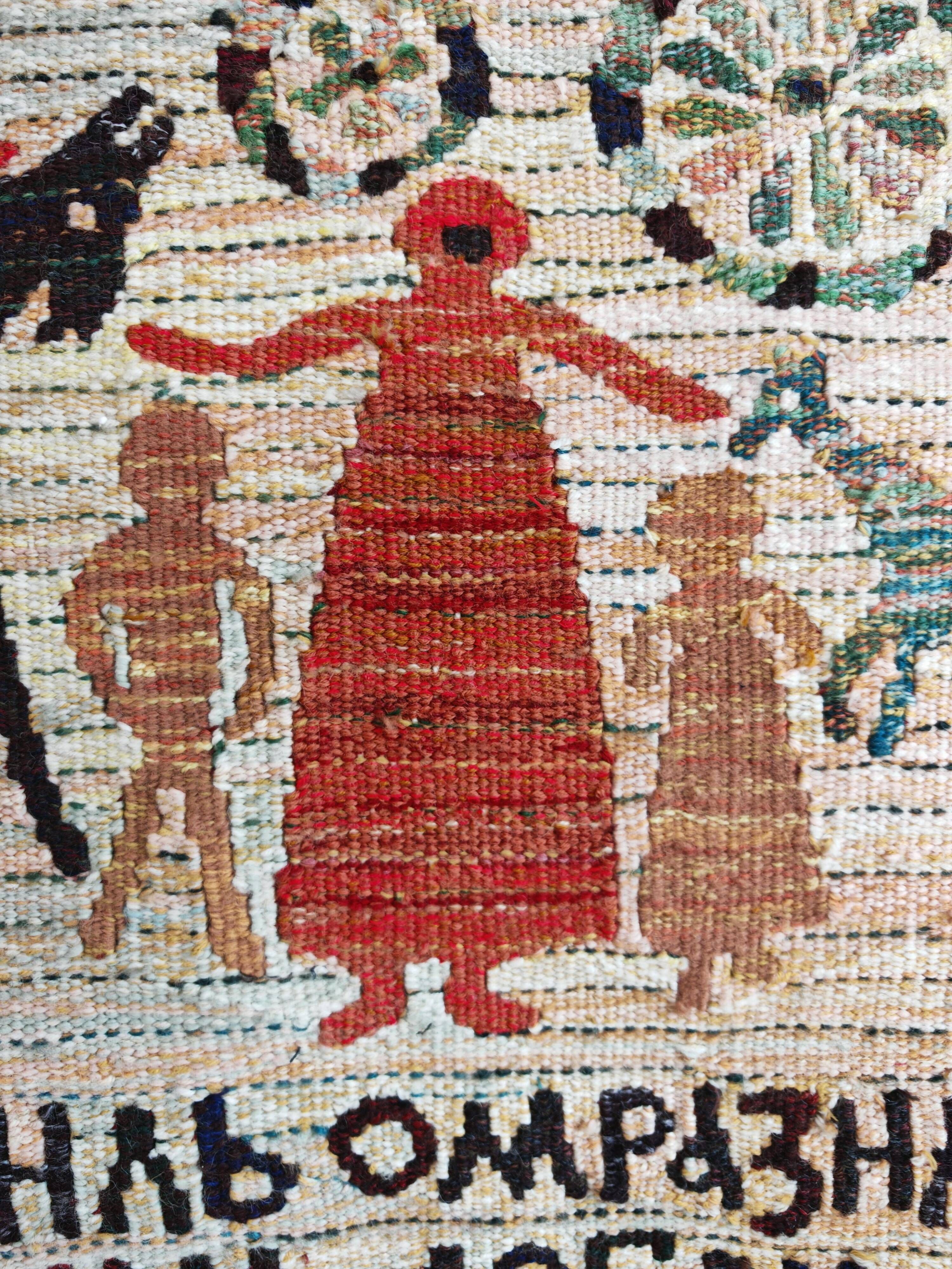 Vintage handwoven tapestry with a folk scene and archaic Slavic writing.
