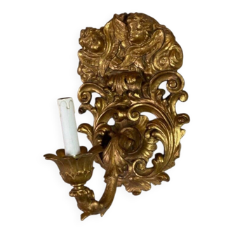 Pair of sculpted and gilded wooden wall sconces topped with two cherub heads, Italy.