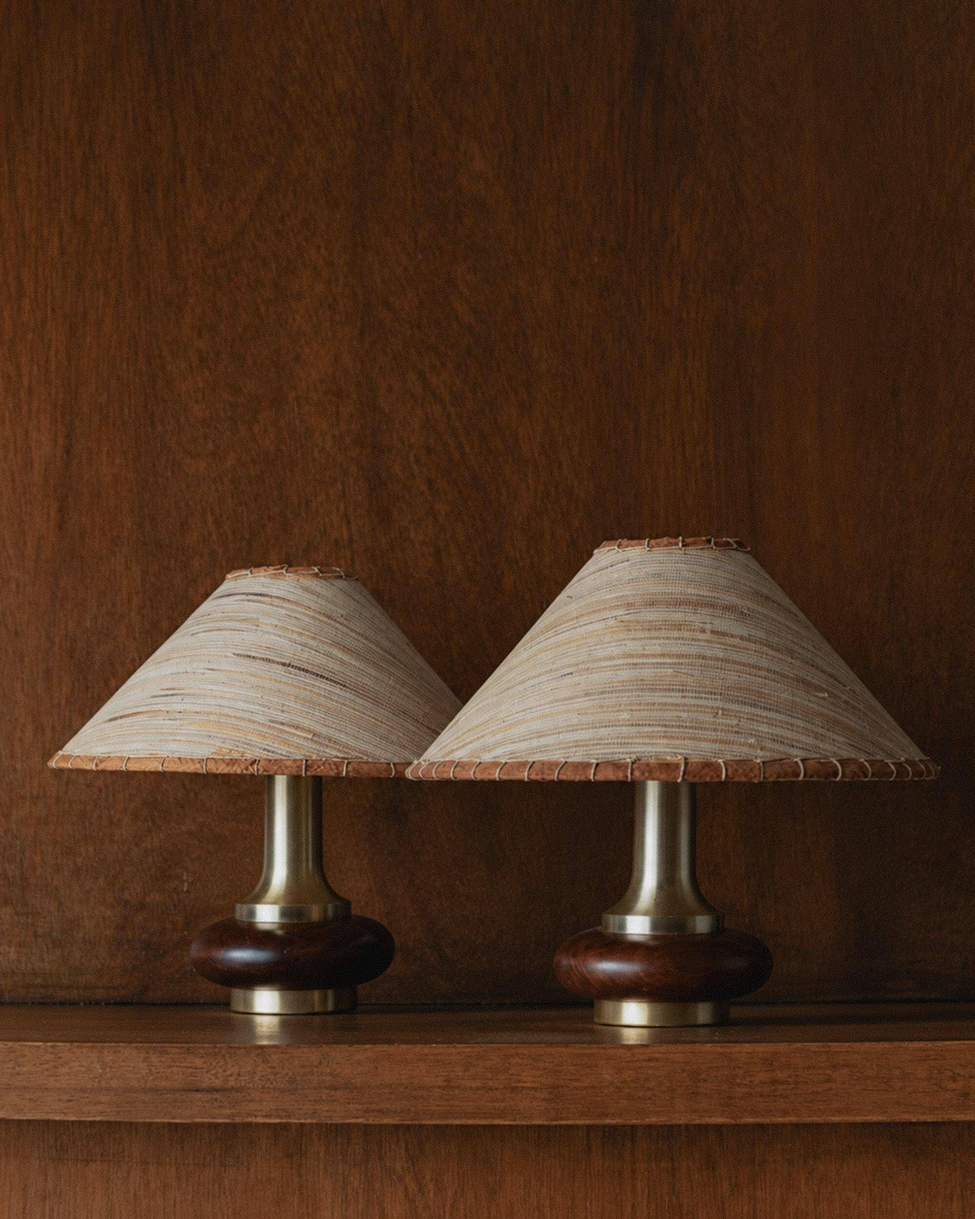 Lot of 2 vintage table lamps from the 1970s, dark wood oval bases with curved brass details, handmade natural fibre lampshades, elegant lighting.