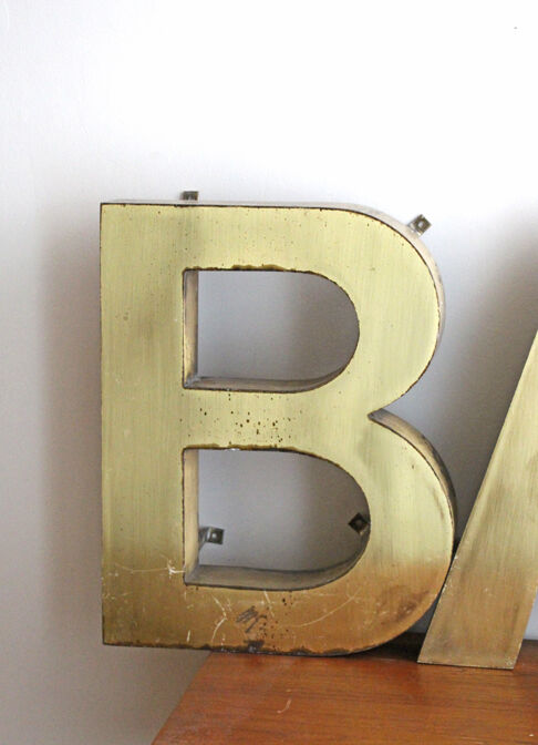 Old brass sign letters, word BAR