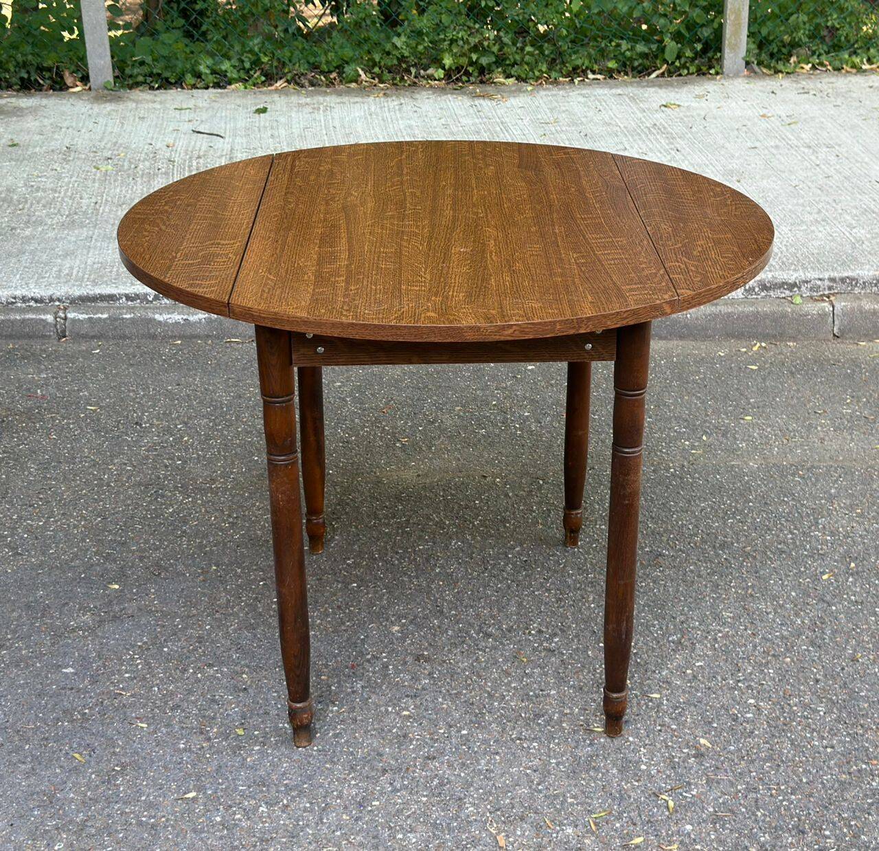 Round kitchen table with extendable leaves in dark wood.