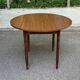 Round kitchen table with extendable leaves in dark wood.