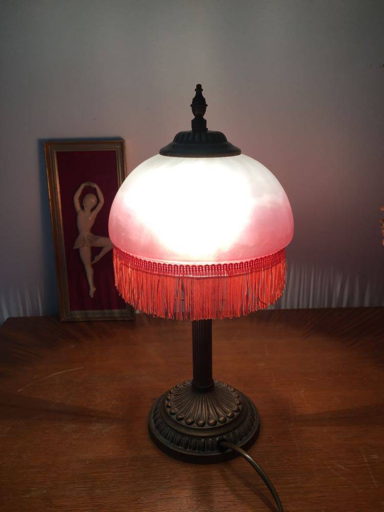 Old table/bedside lamp with glass shade with pink gradients and fringes.