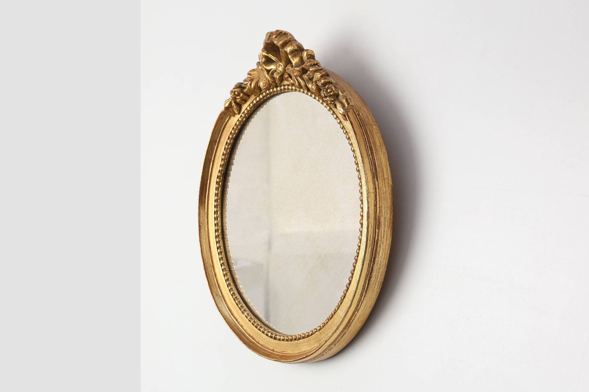 Oval giltwood mirror with rococo-style floral crest, mid-20th century
