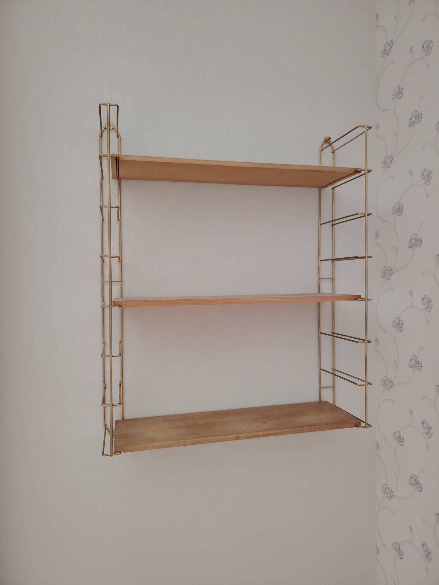 Vintage modular wall shelf in golden steel wire and wood from the 1950s.