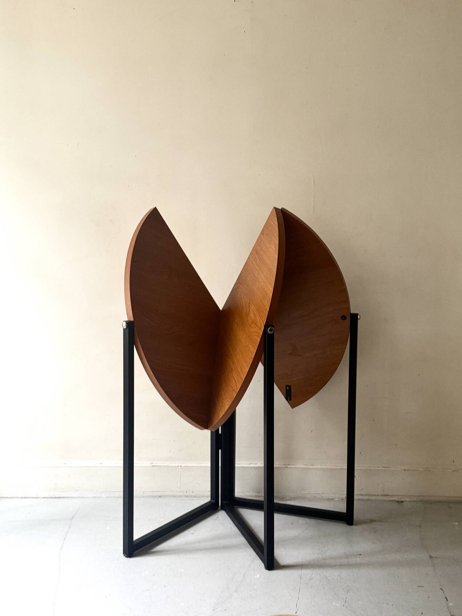 Modernist round folding dining table in wood and metal.
