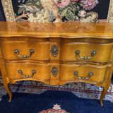 Large bow-fronted chest of drawers in blonde cherry with bronze ornamentation.