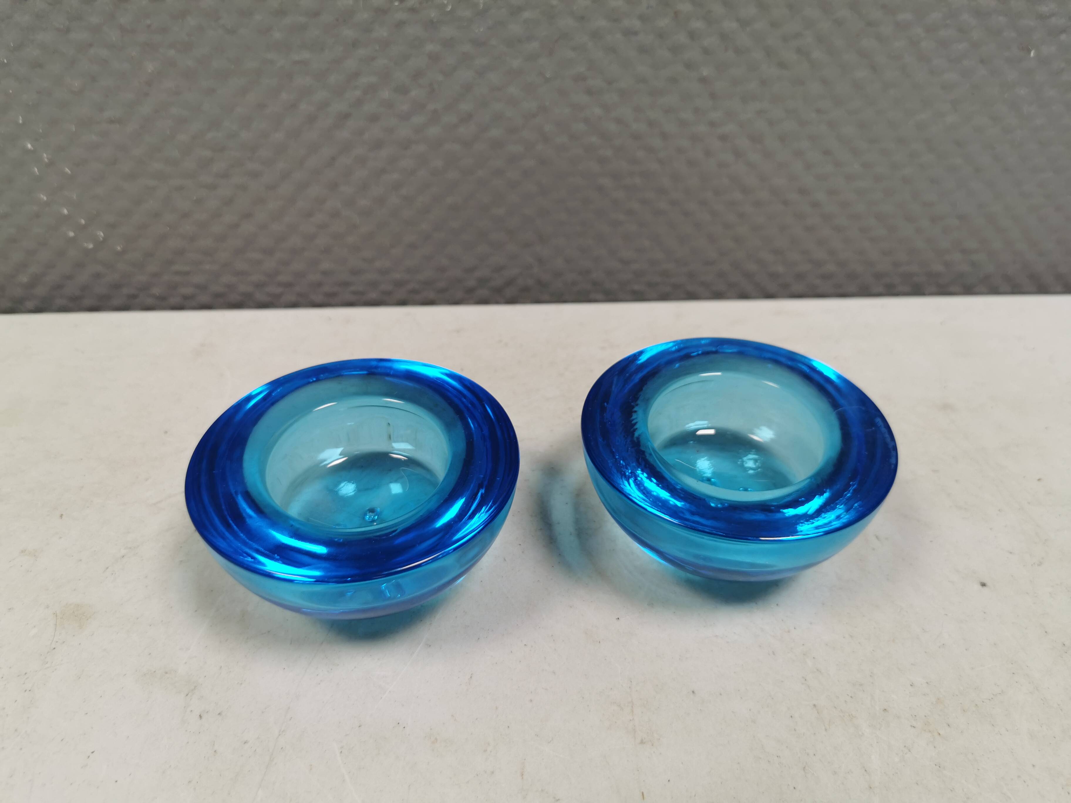 A set of iitalla candle holders in blue transparent glass.