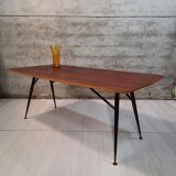 Table à manger en bois de teck et pieds en métal peint.