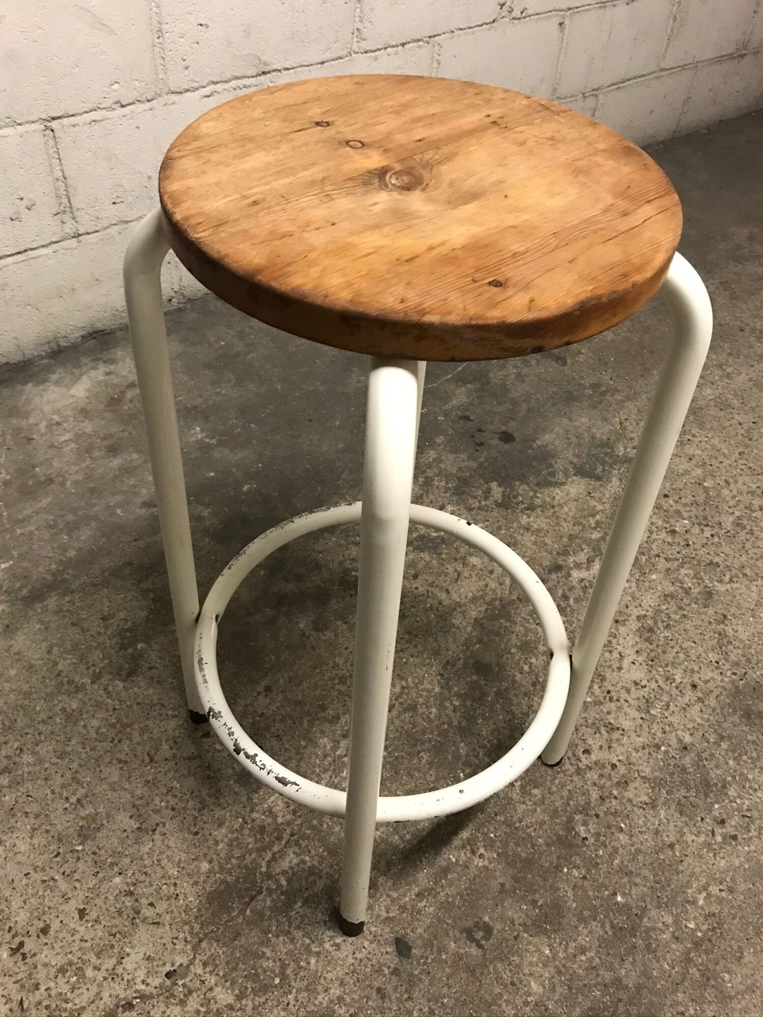 Vintage bar stool in white lace-up, round wooden seat rests circular feet
