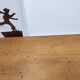 Wall shelf in wood and metal with a decoration of ice skaters.