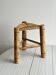 Antique tripod stool in light wood with a woven straw seat.