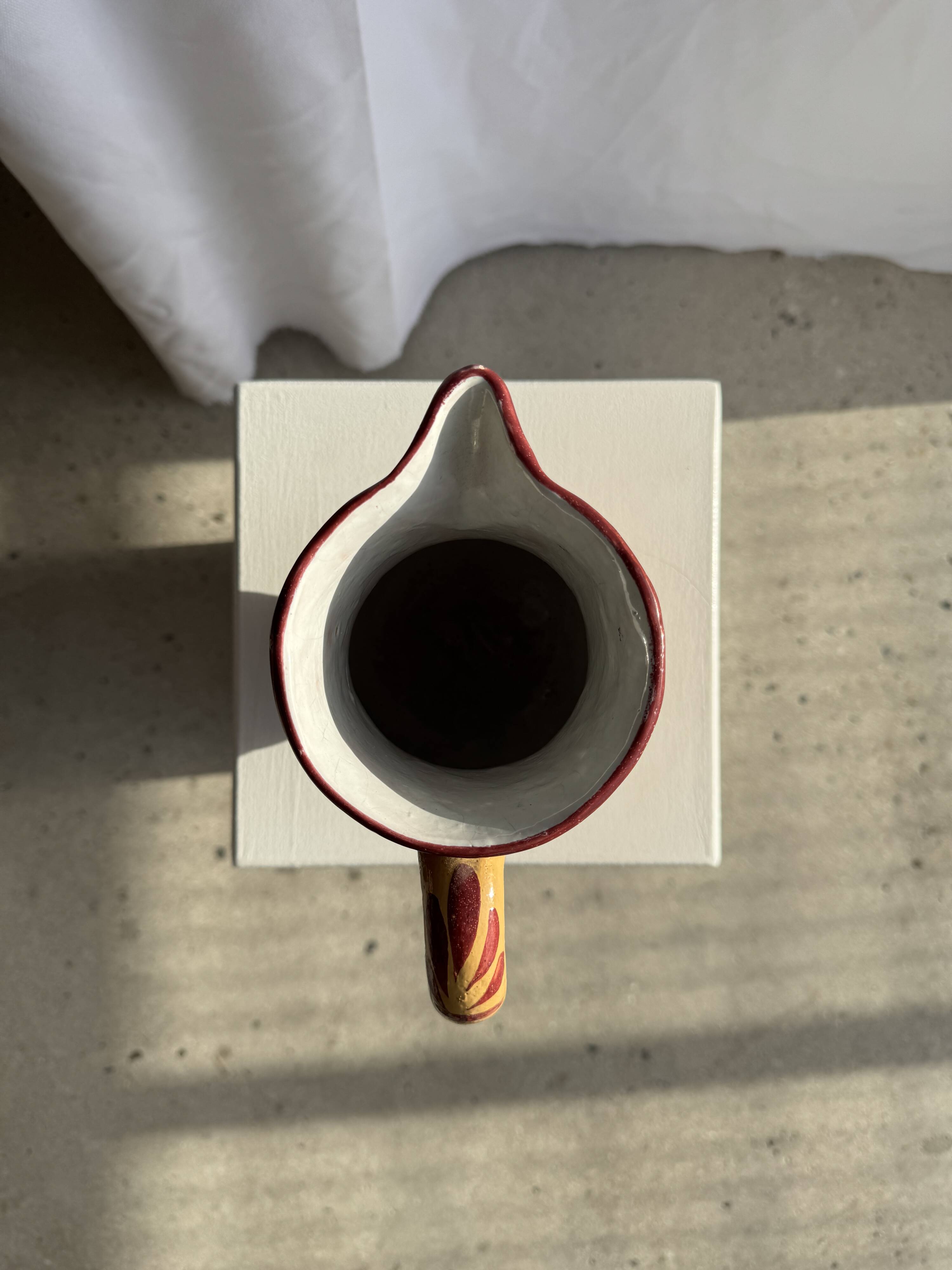 Large antique handmade ochre yellow jug with a pink flower pattern.