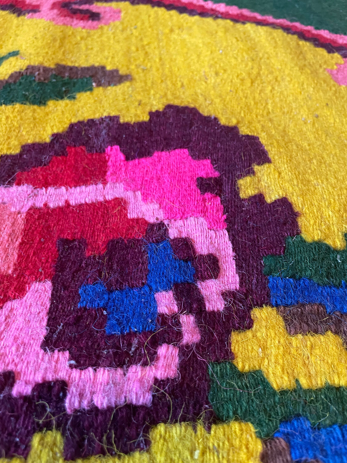 Vintage wool rug with pink flowers on green and yellow background made by hand in Transylvania