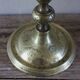 Brass candle holder with flowers and round shape.
