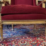 Golden wooden bergère in Louis XVI style upholstered in Bordeaux velvet.