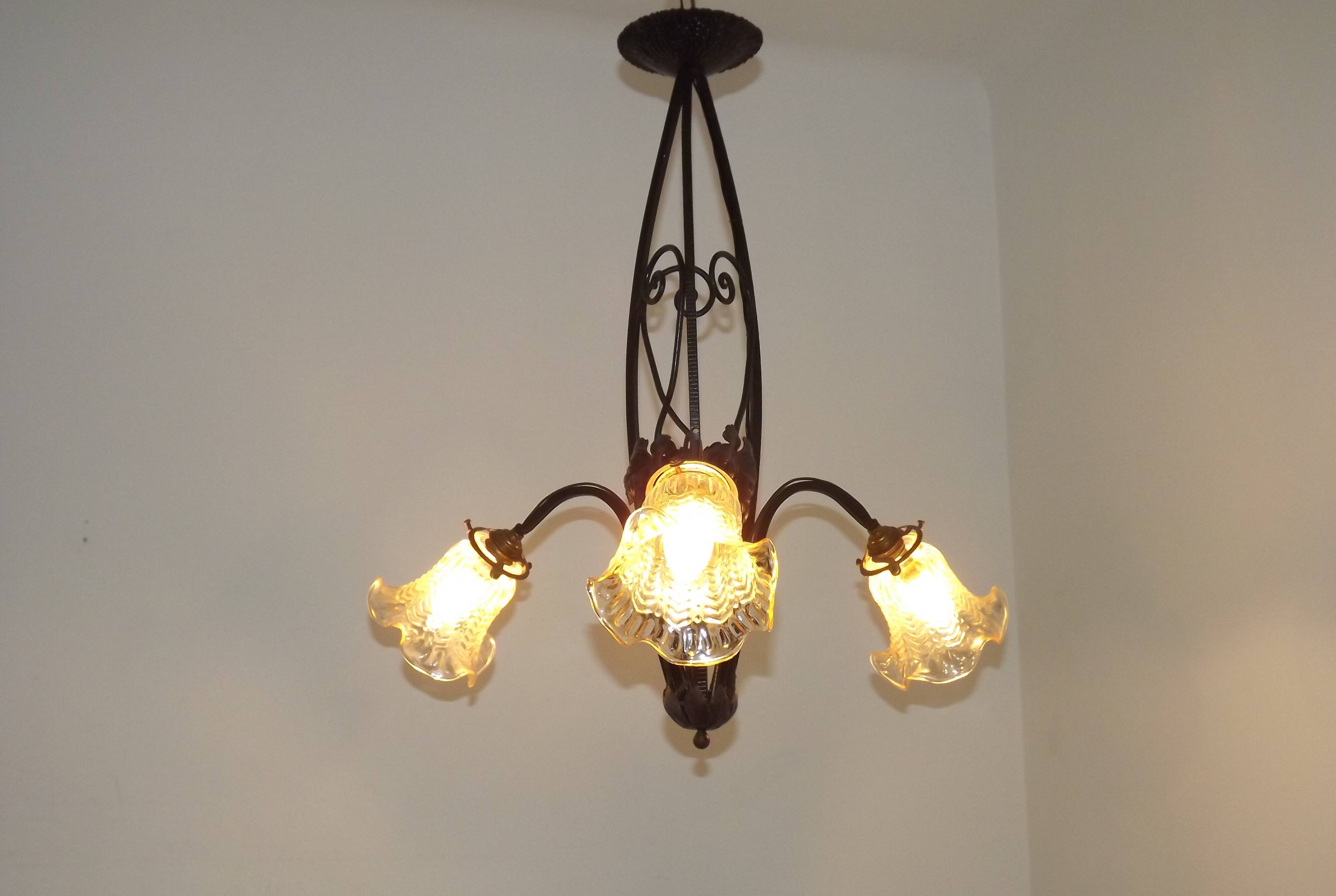 French Art Nouveau leaf detail iron three-light chandelier with amber glass shades.