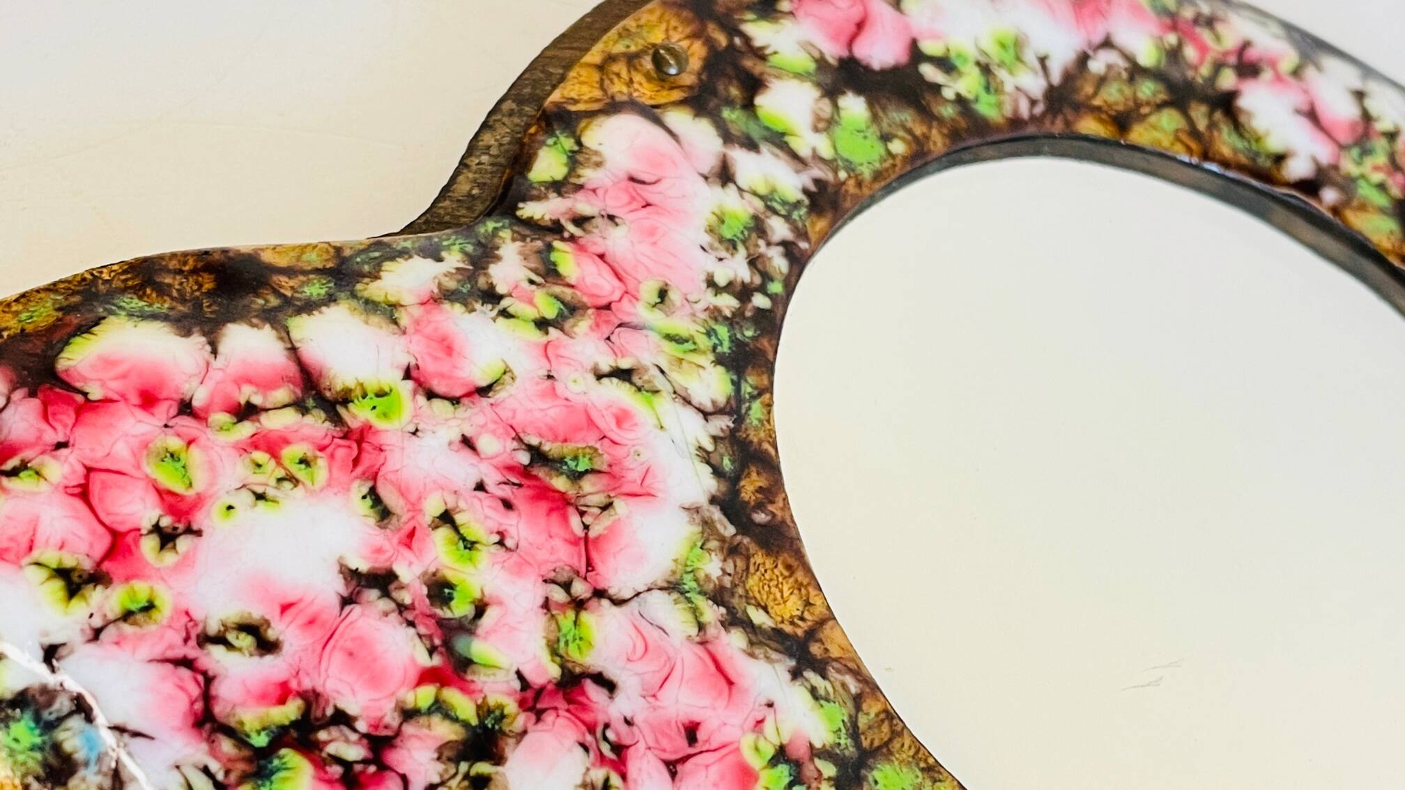 Vintage enameled metal hand mirror on wood