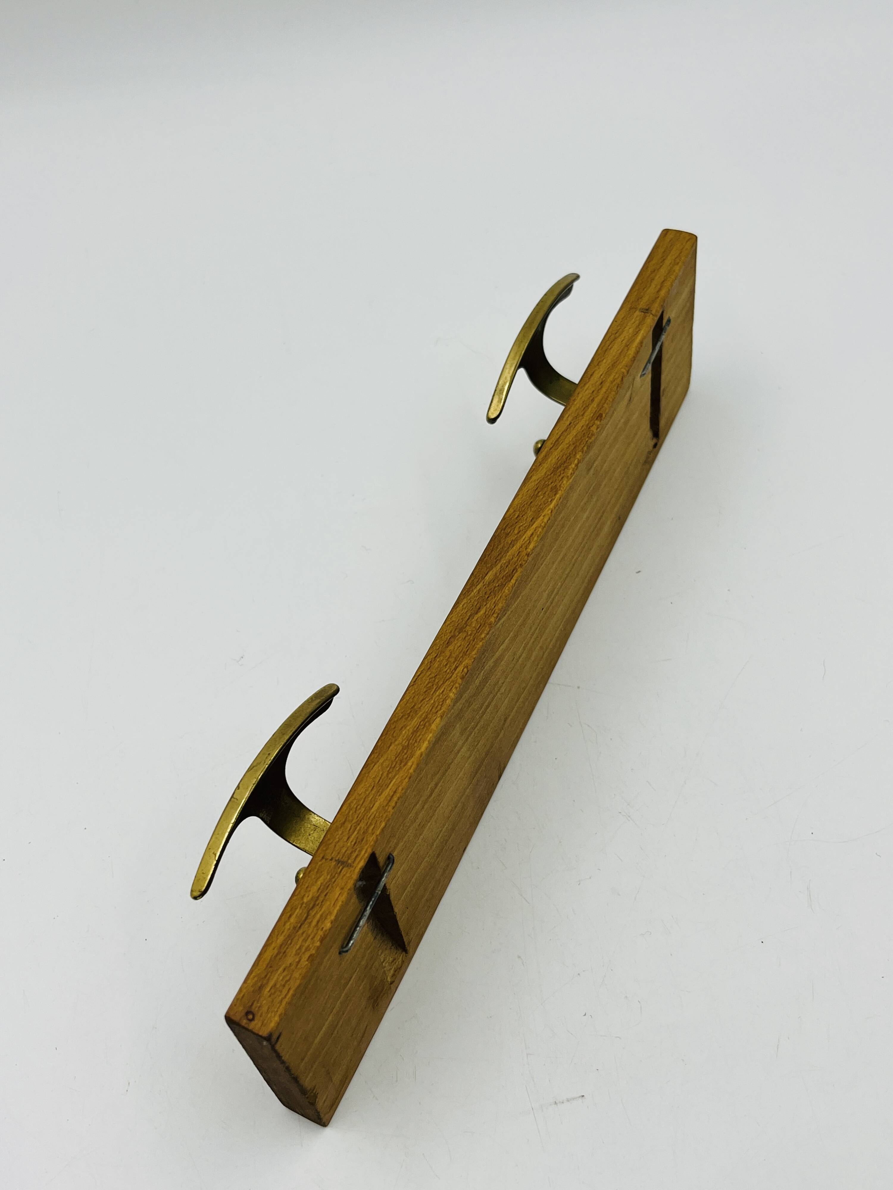 Vintage wall coat rack in brass and wood design.