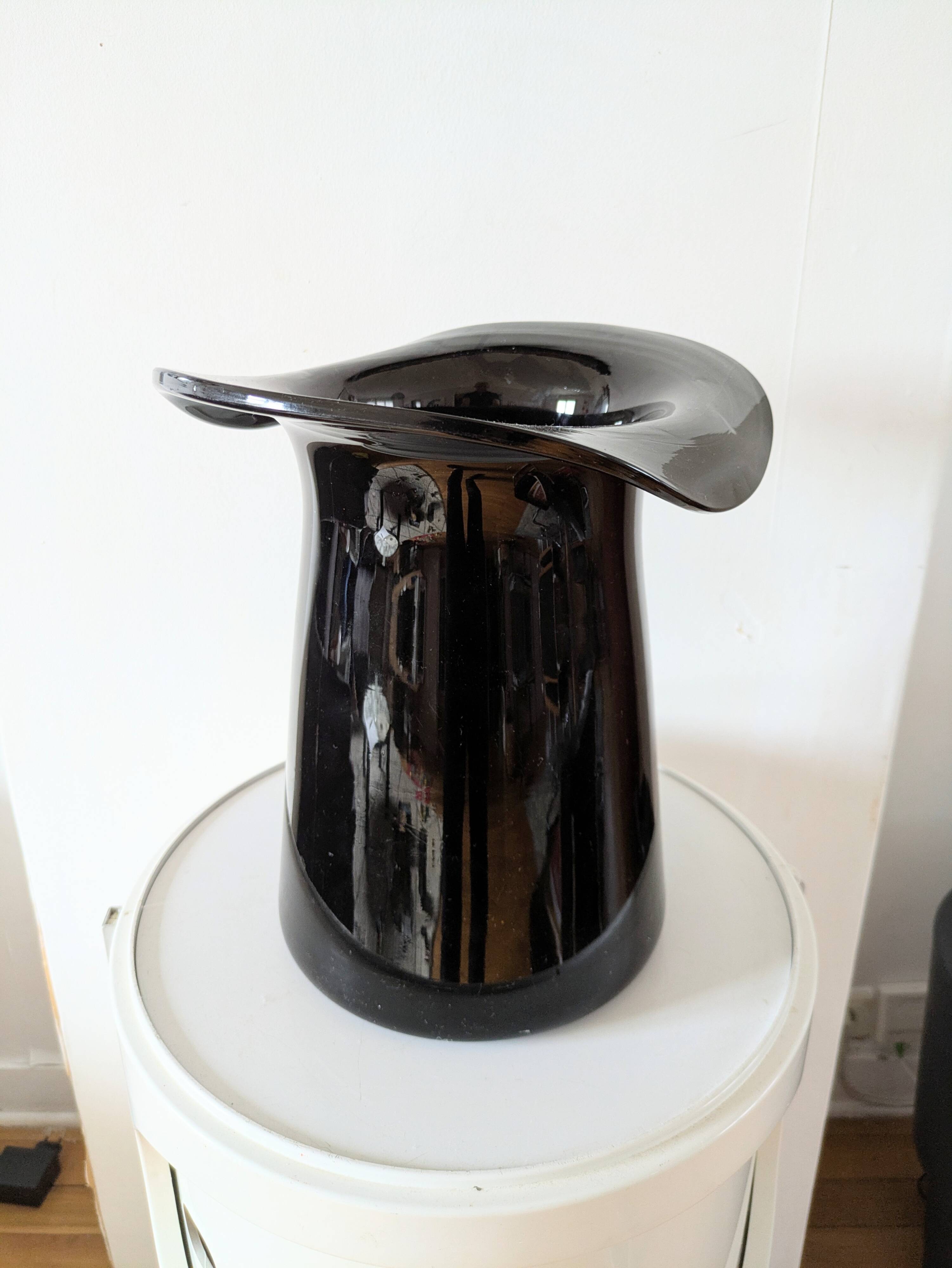 Large black glass vase topped with a 70s hat