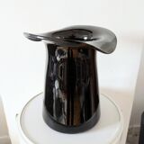 Large black glass vase topped with a 70s hat