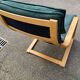 Scandinavian rocking chair with curved wood and green leather, IKEA Poäng.