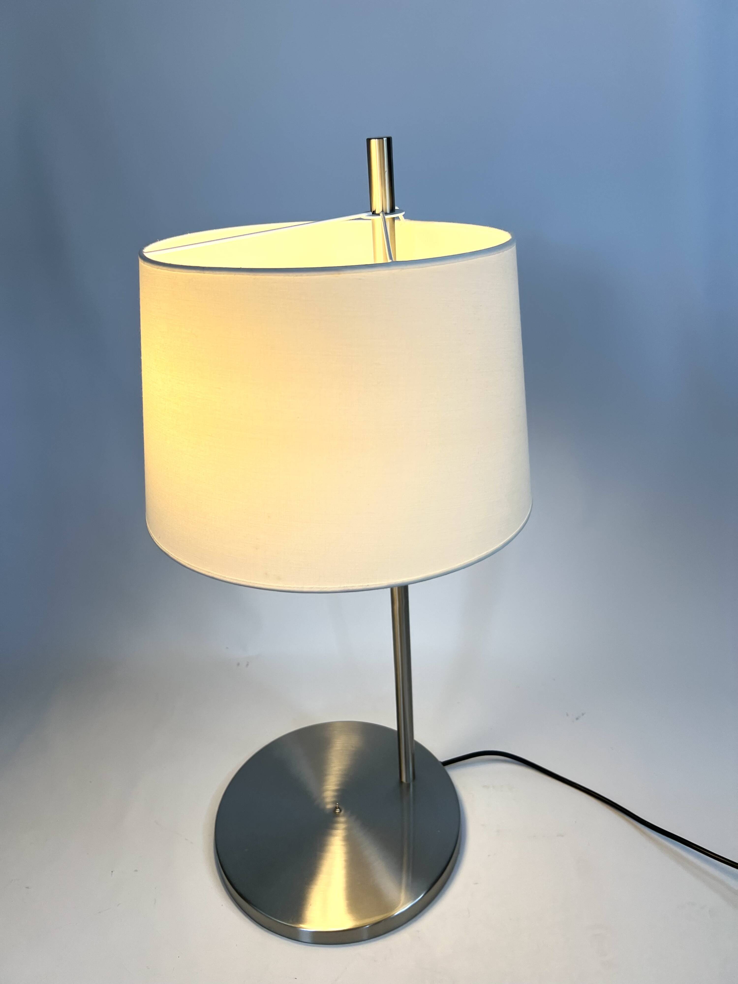 Large brushed metal table lamp with an ecru shade.