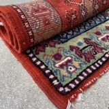 Vintage hand-knotted wool rug with polychrome decoration on a red, blue, green background 150 x 63 cm
