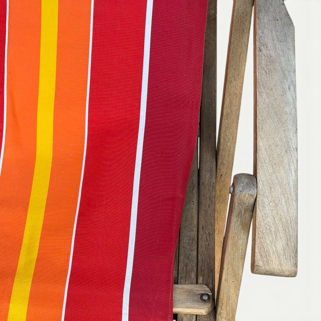 Vintage deck chair with red and orange striped fabric, original patina.