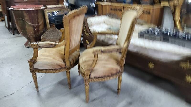 A pair of gilded wooden armchairs in the Louis XVI style.