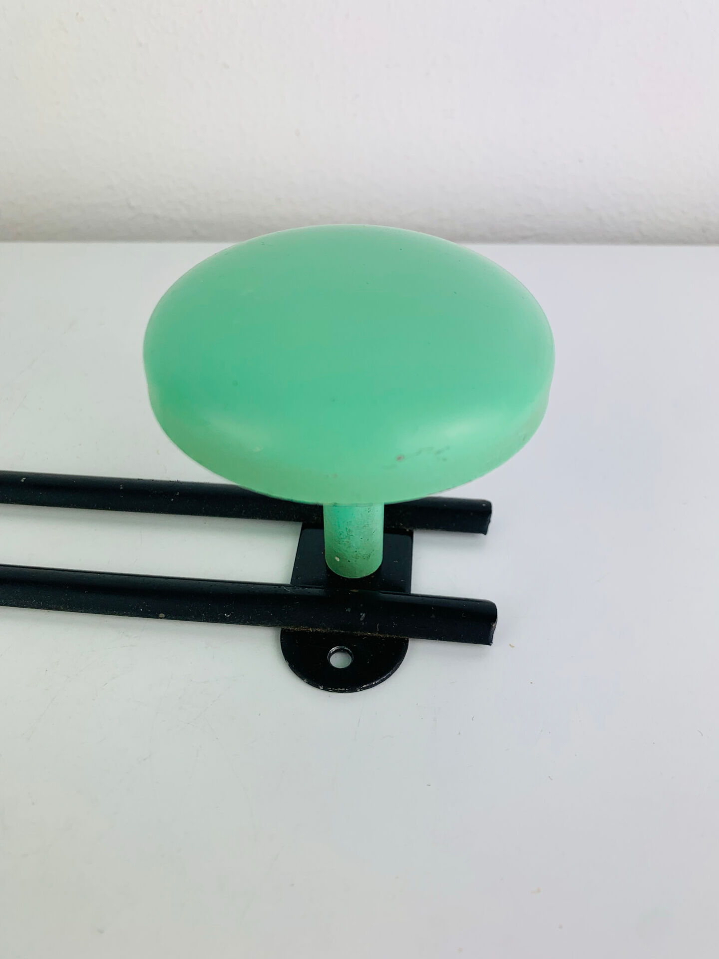 Wall-mounted coat rack with 2 green hooks from the 1950s.