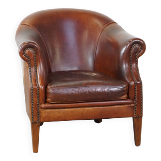 Un fauteuil club robuste mais confortable en cuir de mouton et fini avec des clous décoratifs