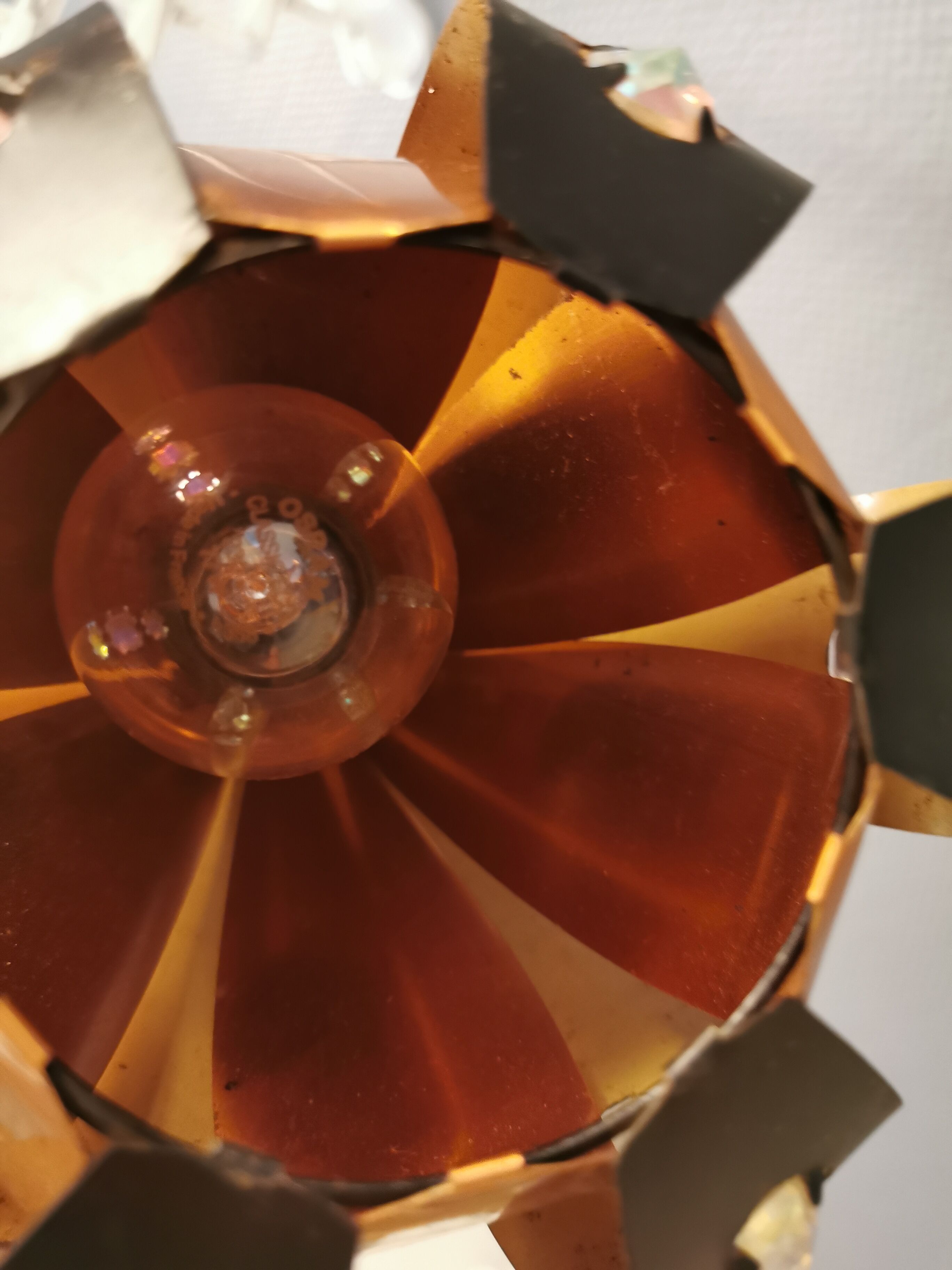 Hanging lamp in thin metal pieces, copper colored and black with prisms.