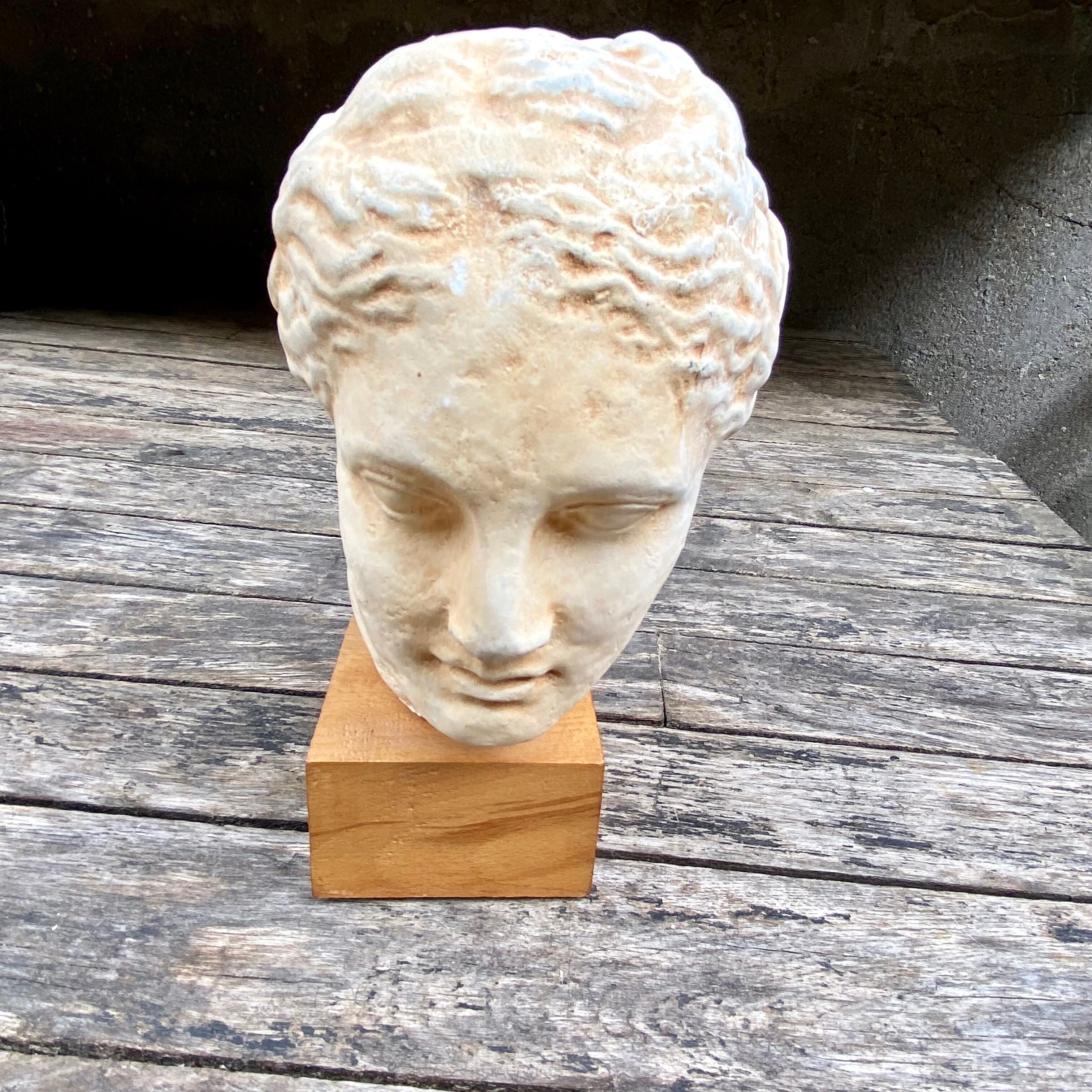 Plaster head of an ancient goddess on its wooden base