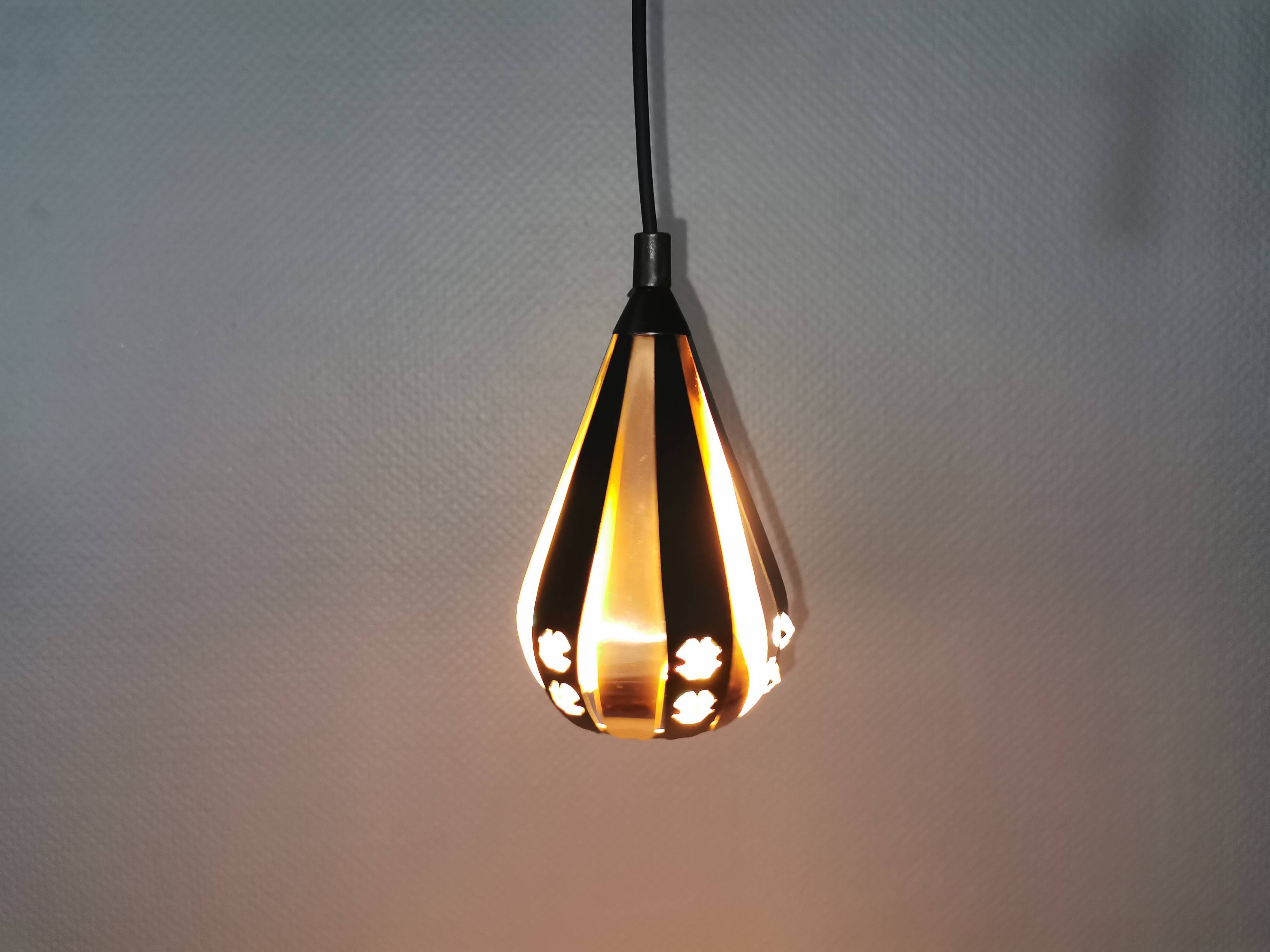A teardrop-shaped pendant lamp made of copper, black metal, and prisms.