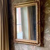 Miroir ancien en bois sculpté doré à décor de fleurs