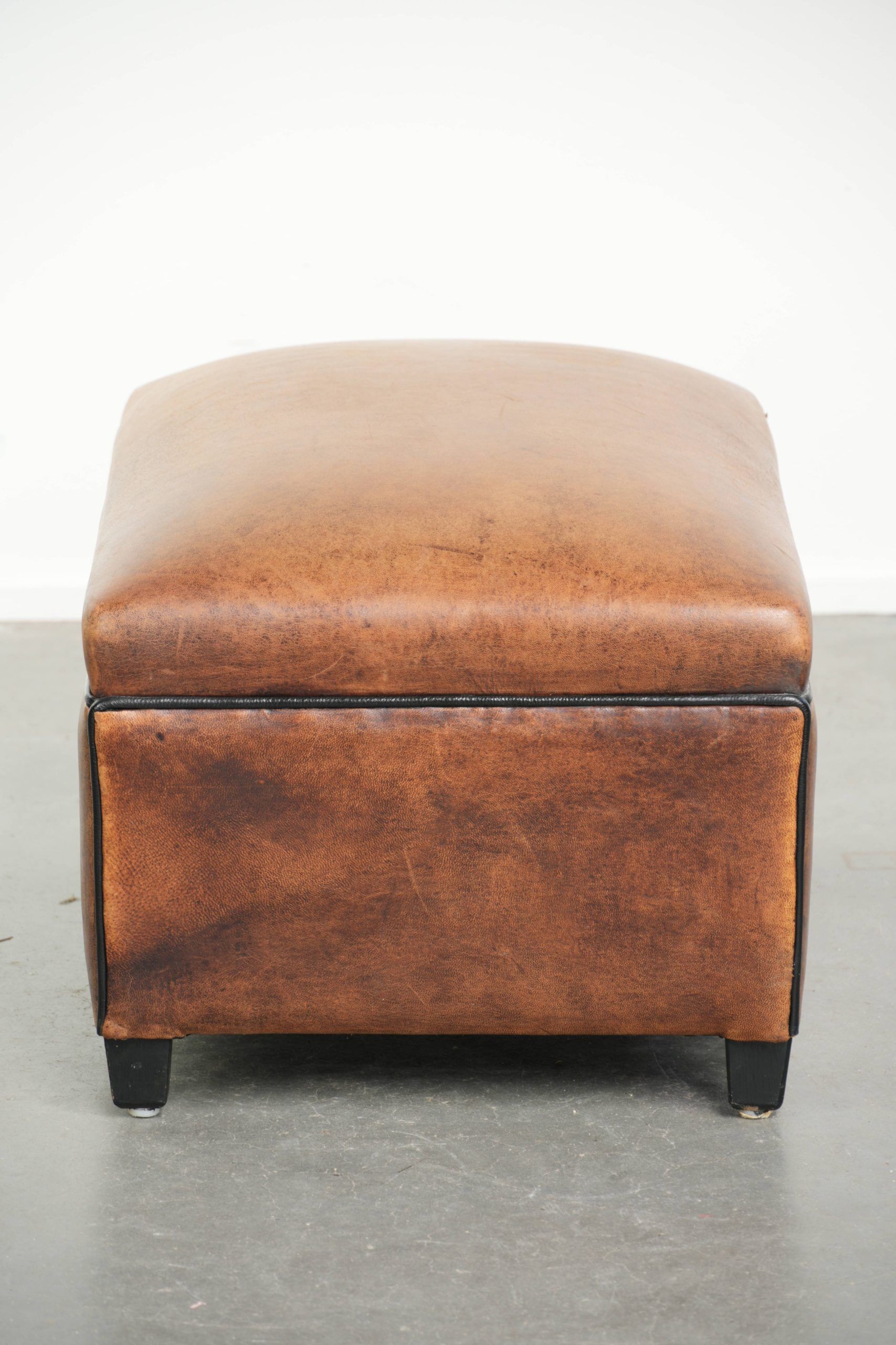 Characterful sheepskin footstool/ottoman finished with black piping