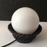 Table lamp with black porcelain support in the shape of a woven basket and opaque glass ball globe