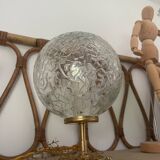 Small handcrafted globe lamp with a cracked finish and a golden brass base.
