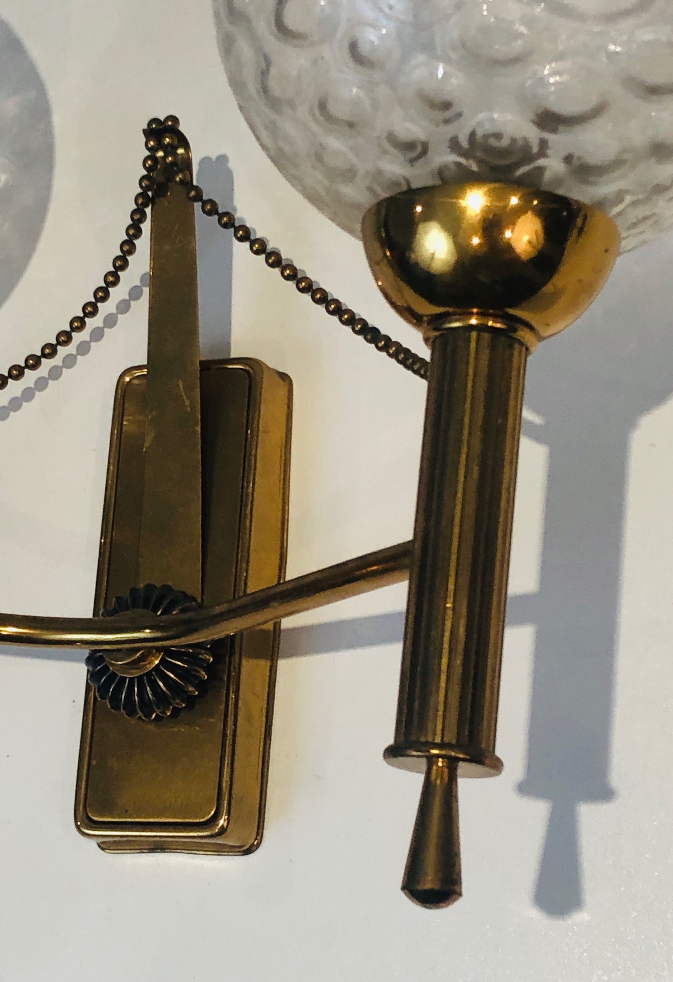 Pair of brass wall lights with glass globes. Around 1970.