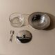 Vintage 1970s condiment pot made of glass and stainless steel with a lid, complete with a matching spoon.