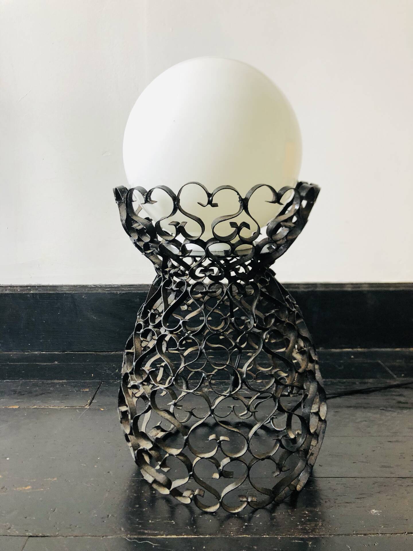 Handcrafted wrought iron lamp with a white opaline globe.