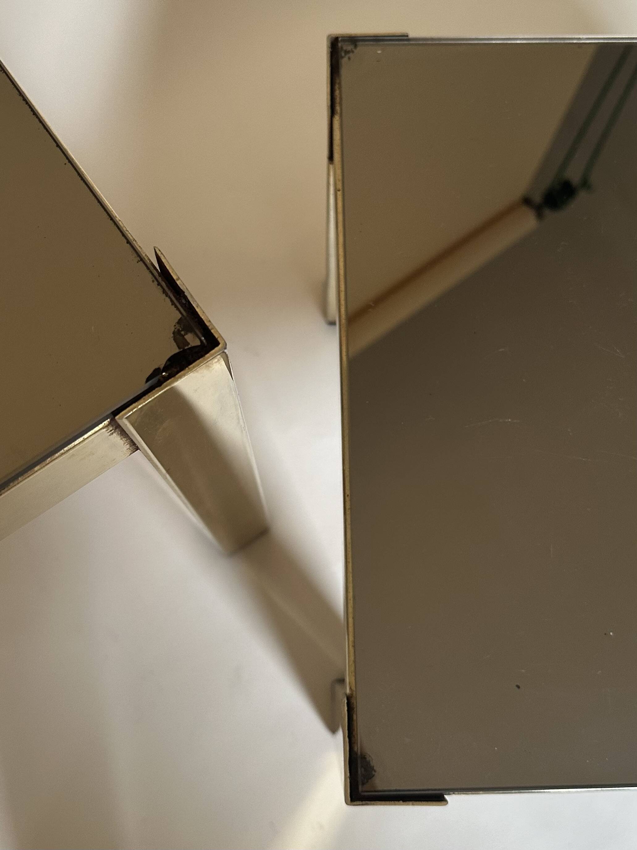 Set of three nesting side tables in brass and smoked mirror.