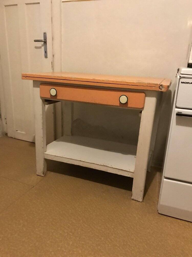 Vintage wooden kitchen table in orange and white with a drawer and low shelf.
